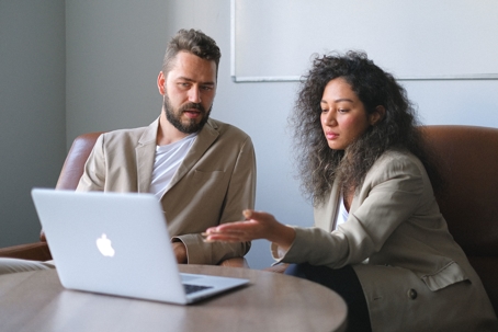 A man and woman review a laptop, likely discussing website content to publish.