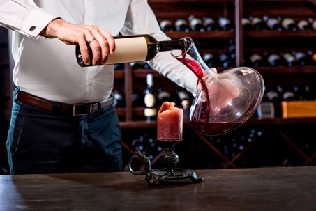 person pouring wine into decanter