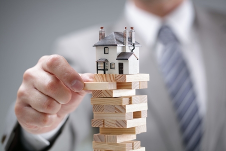 hand pulling wooden block under model of house